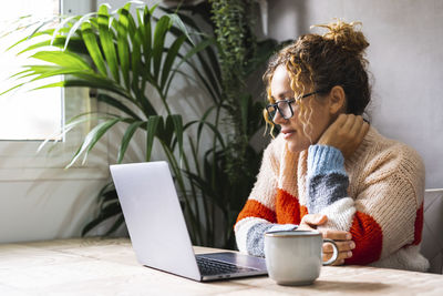 Young woman using laptop while sitting on table