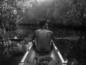 Rear view of man in boat against river