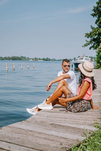 Woman sitting by lake against sky