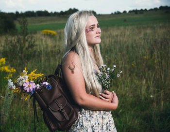 Beautiful young woman standing by flower field