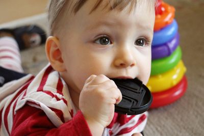 Close-up of baby with camera lens cover in mouth