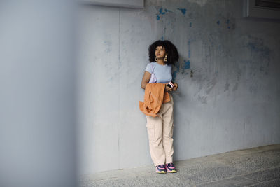 Female teenager standing against wall