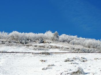 Snow covered landscape against clear blue sky