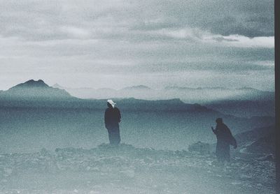 People standing on snow covered land against sky