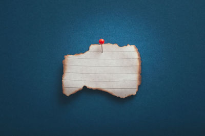 Close-up of heart shape on paper against blue background