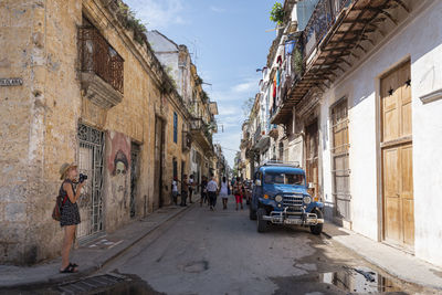 Side view of woman photographing while standing on street