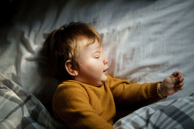 Close-up of cute boy lying on bed at home