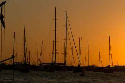 Sailboats sailing in sea against clear sky during sunset