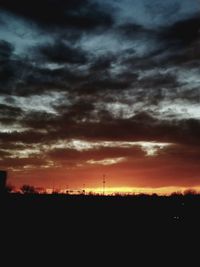 Silhouette of field against dramatic sky during sunset