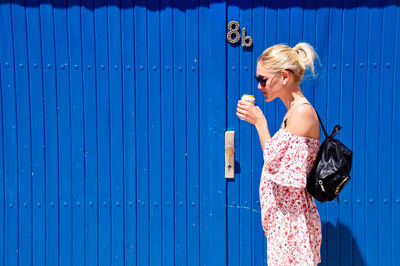 Full length of woman standing against blue wall