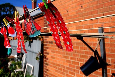 Christmas decorations hanging on clothesline against brick wall