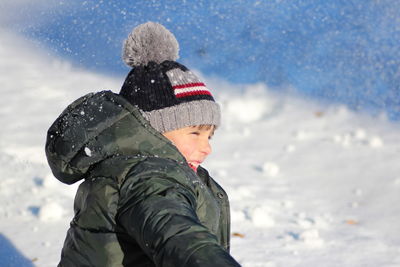 Smiling boy playing with snow during winter