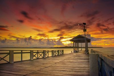 Pier over sea against sky during sunset