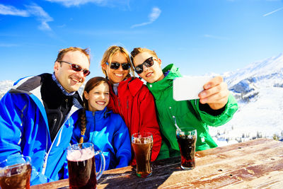Portrait of happy friends standing on snow covered mountain