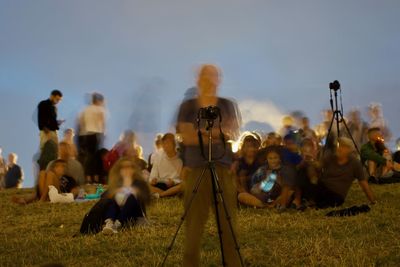 People photographing on field against sky