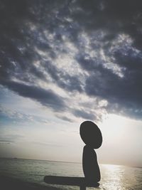 Silhouette rocks by sea against sky during sunset