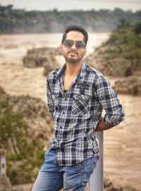 Portrait of young man wearing sunglasses standing outdoors