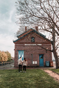 Low angle view of woman standing by building against sky