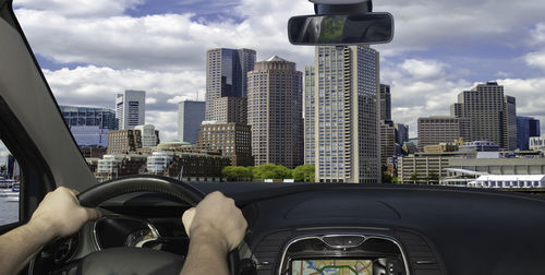 Man driving car in city against sky