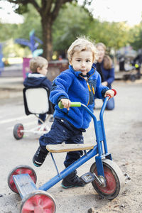 Portrait of boy playing with tricycle on playground