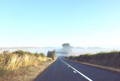 Road passing through landscape against clear sky