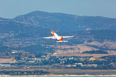 Bird flying over mountain against sky