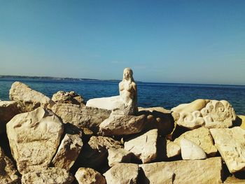 Rocks on beach against clear blue sky