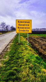 Information sign on field against sky