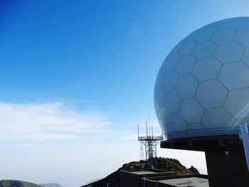 Low angle view of communications tower against blue sky