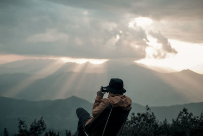 A man is taking the photo on the peak and looking at the sky explosions