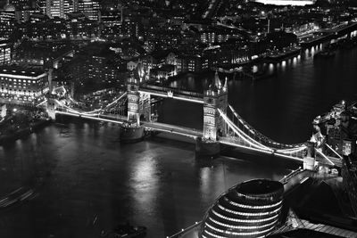 Illuminated bridge over river in city at night