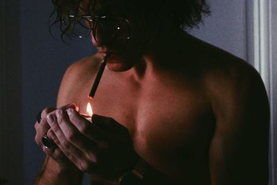 Close-up of shirtless man smoking cigarette at home