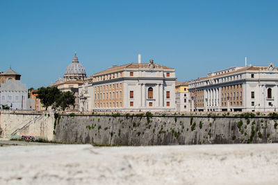 Buildings in city against clear blue sky