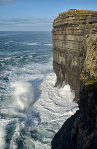 Rock formation at sea against sky