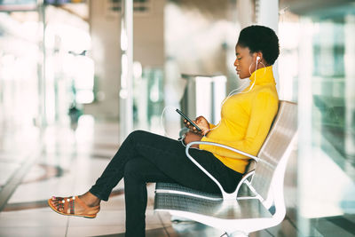 Beautiful african woman sitting on a chair in the waiting room, waiting for a subway train 