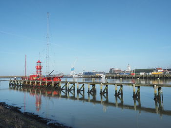 Lighthouse at harbor in sea against clear sky