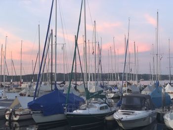 Sailboats moored at harbor against sky during sunset