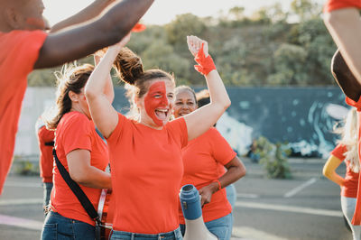 Rear view of friends with arms raised standing on street