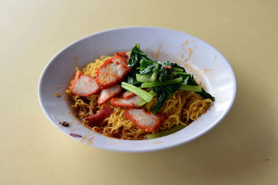 High angle view of wonton noodles with meat in white bowl on table