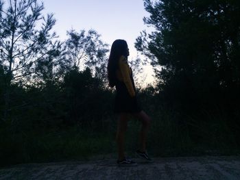 Woman standing by tree against plants