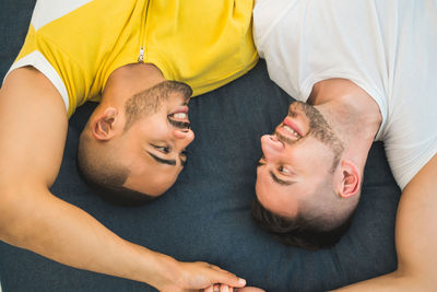 High angle view of gay couple lying down bed