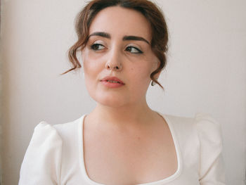 Close-up portrait of a young woman against wall