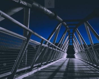 Low angle view of footbridge against clear blue sky at night