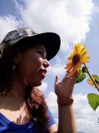 Portrait of young woman with flowers against sky