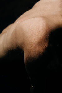 Close-up of shirtless man over black background