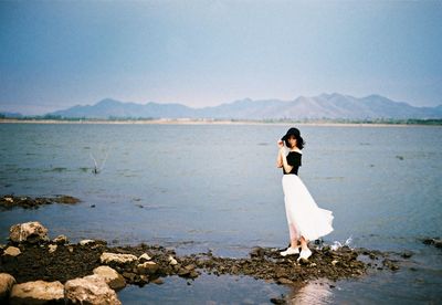 Rear view of woman standing in sea against sky