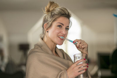Woman wrapped brushing teeth while standing at home