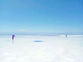 Woman standing on salt flat at salar de uyuni against sky