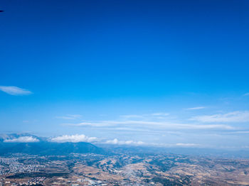 Aerial view of city and mountains against blue sky