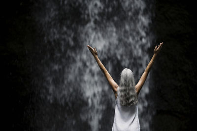 Beautiful senior woman standing in front of a tropical waterfall